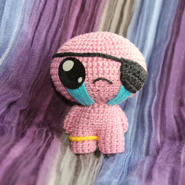 Binding of Isaac Cain Crochet Amigurumi over colorful linen