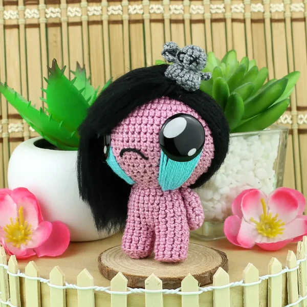 Binding of Isaac Eve Crochet Amigurumi next to plants and flowers