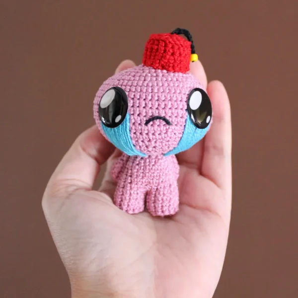 Binding of Isaac Judas Crochet Amigurumi on holding hand over brown background