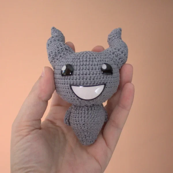 Binding of Isaac Lil Brimstone Crochet Amigurumi on holding hand over brown background