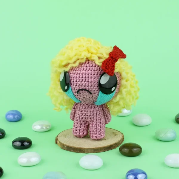 Magdalene Crochet Amigurumi next to pearl stones over green background