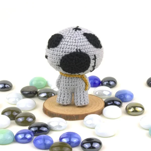 Binding of Isaac Keeper Crochet Amigurumi next to pearl stones over white background