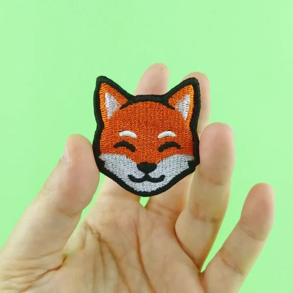 Orange Kawaii Fox Embroidered Patch hold in hand over green background