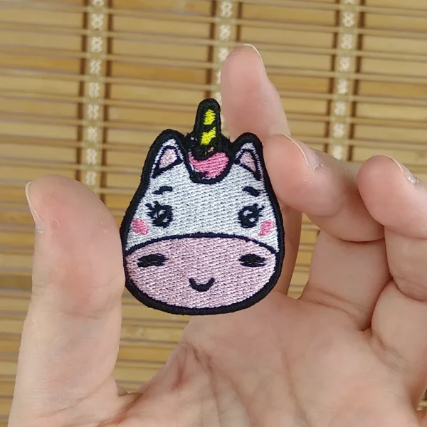 Small White and Pink Kawaii Unicorn Embroidered Patch on holding hand