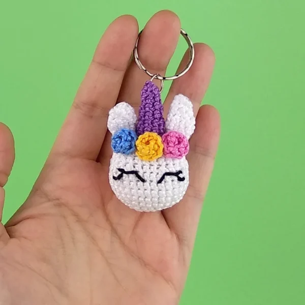 Kawaii Unicorn Keychain on holding hand over green background