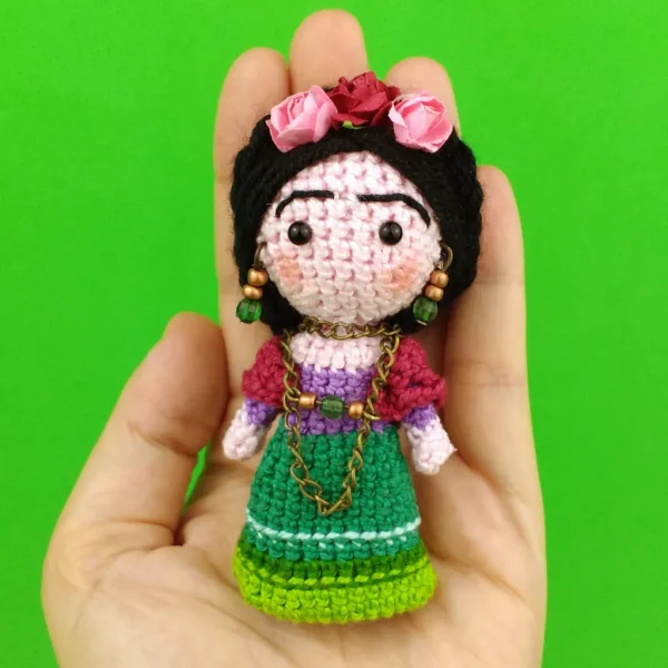 Mexican Doll Crochet Amigurumi on holding hand over green background