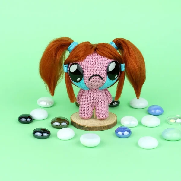 Binding of Isaac Bethany Crochet Amigurumi next to pearl stones over green background