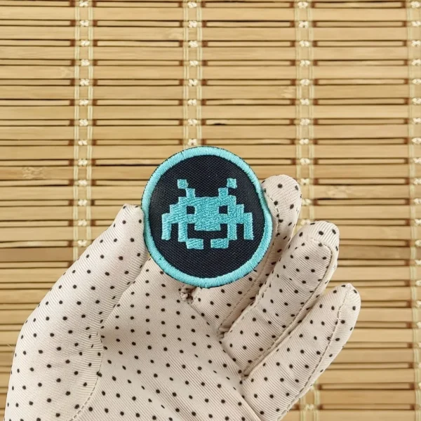 Space Invaders blue Pixel Alien Embroidered Patch on holding hand