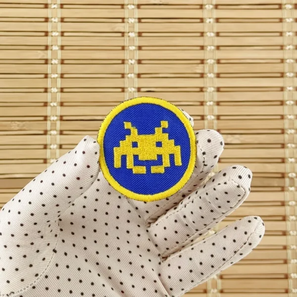 Space Invaders yellow and blue Pixel Alien Embroidered Patch on holding hand