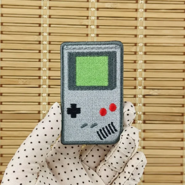 Grey Handheld Game Boy Console Embroidered Patch on holding hand