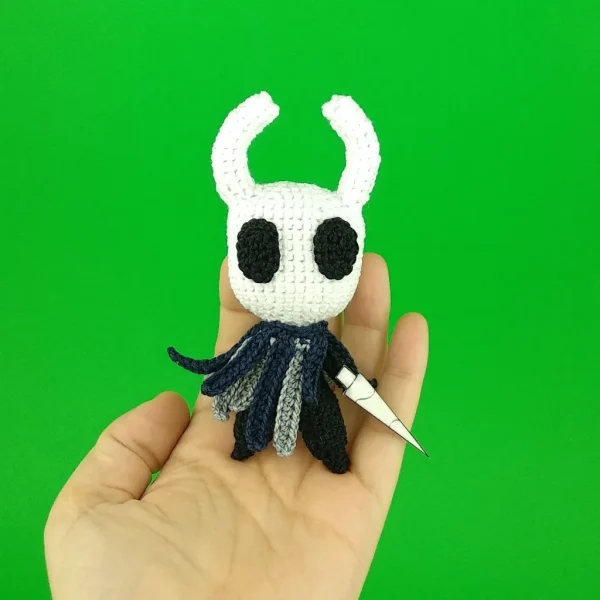 knight Crochet Amigurumi on holding hand over green background