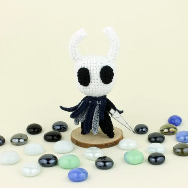 knight Crochet Amigurumi next to pearl stones over green background