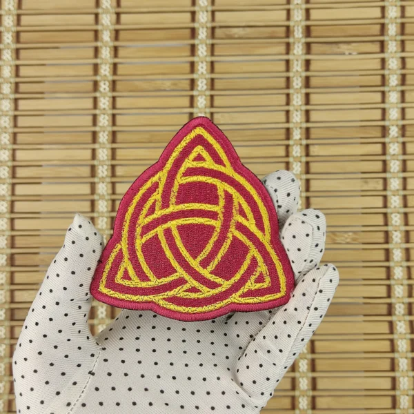 Embroidered patch of a red and yellow Celtic knot size M in hand