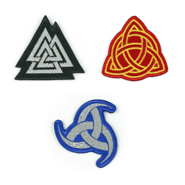 Embroidered patches of a red and yellow Celtic knot, a black and grey Odin talisman and an Odin's three horns on a white background