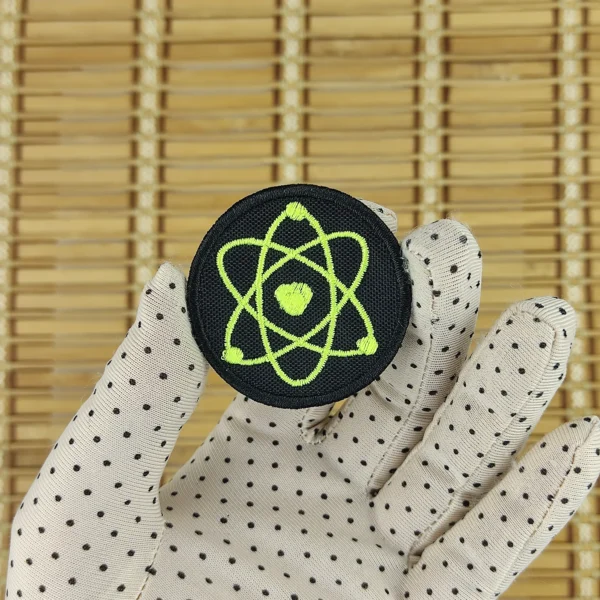 Neon yellow atom embroidered patch in hand